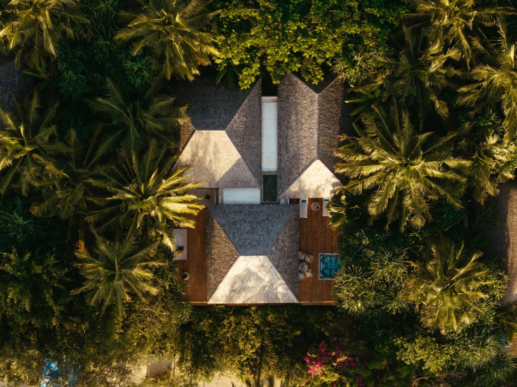 Aerial view of a luxury villa surrounded by lush palm trees, featuring a private pool.
