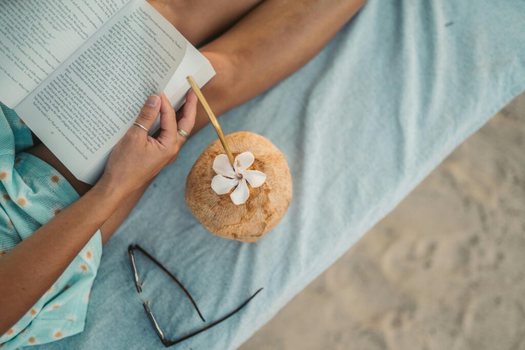 pexels-photo-5858998-5858998 Woman reading a book with a refreshing coconut drink on a beach in Zanzibar.